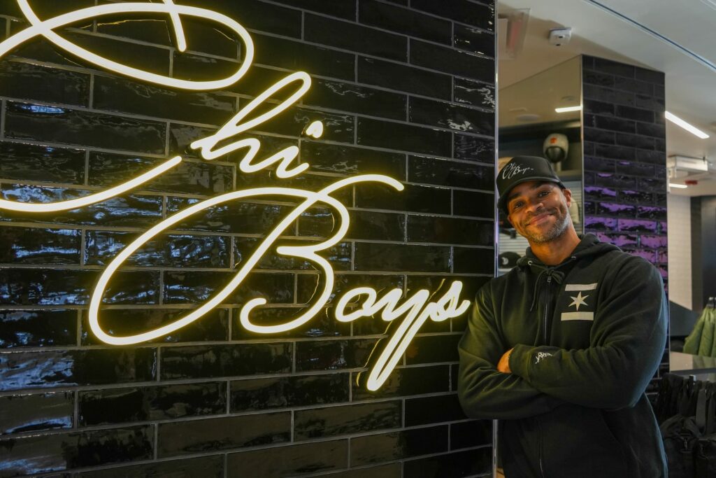 DeShawn Murry standing in front of the sign to his new shop, ChiBoys at Chicago O'Hare Airport